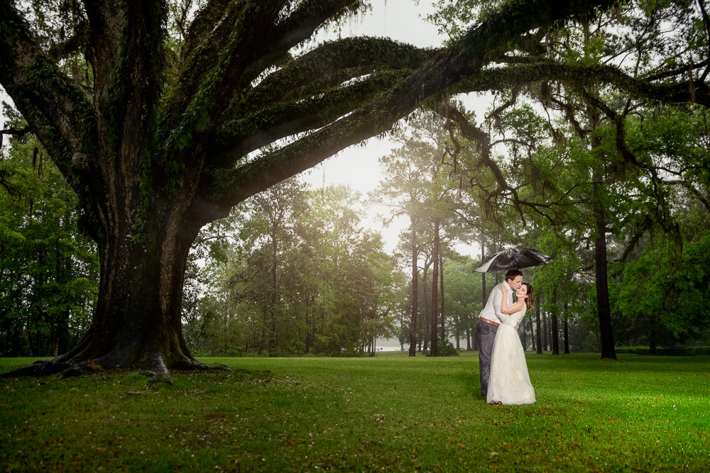 Couple hugging under umbrella in the rain, Fun Engagement Session at Eden Garden and Fort Pickens, Lazzat Photography, engagement photos