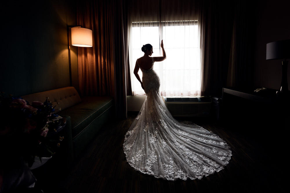 Bride looking out the window, lace wedding dress, Holiday Inn Express Pensacola Downtown, Classic Pensacola Wedding, Lazzat Photography, Florida Wedding Photographer