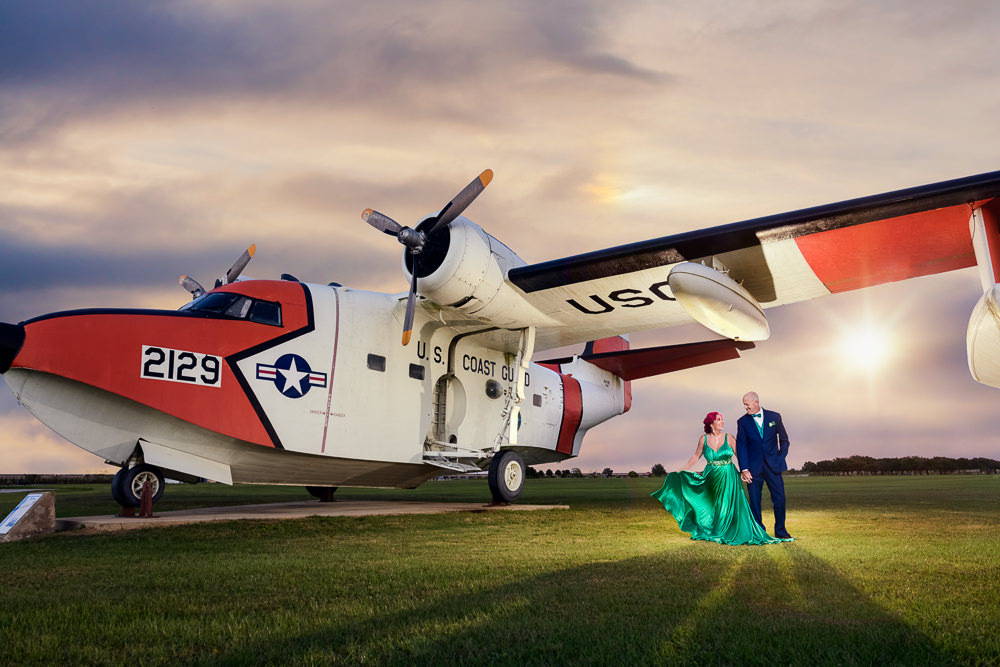 Couple next to a Coast Guard plane, green formal gown, pink hair, EPIC couple shoot, Lazzat Photography